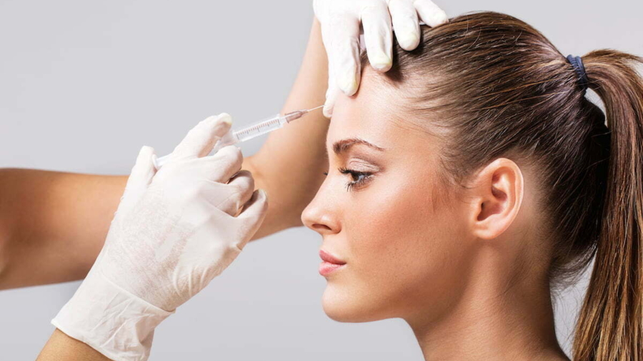 Side view of a young woman receiving botox injection.