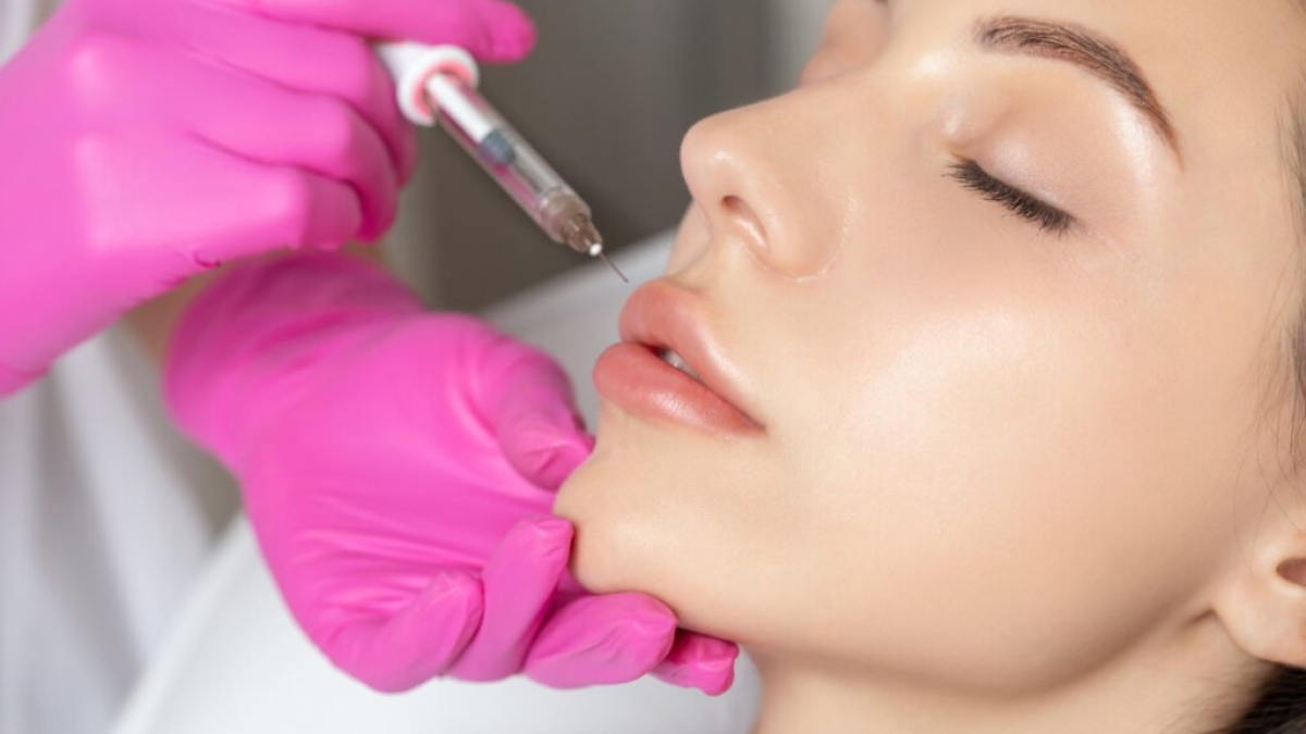 Woman with beautiful clean skin. Cosmetologist does injections for lips augmentation and anti wrinkle of a beautiful woman. Women's cosmetology in the beauty salon. (Woman with beautiful clean skin. Cosmetologist does injections for lips augmentation